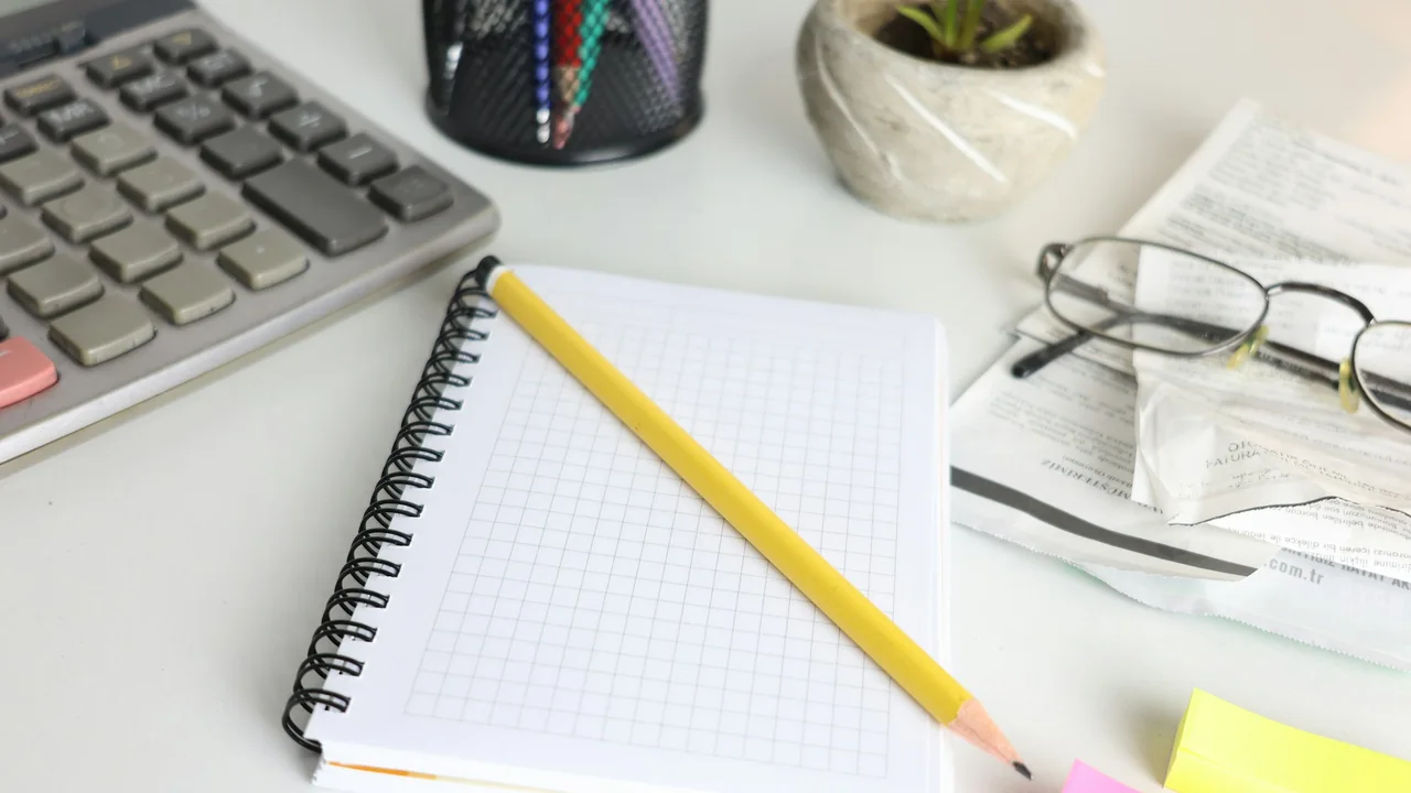 Calculator, notebook, pencil, glasses and receipts on an office desk