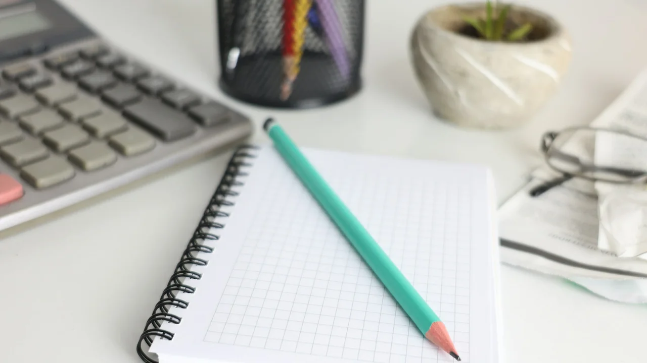 Calculator and notebook arranged on a desk