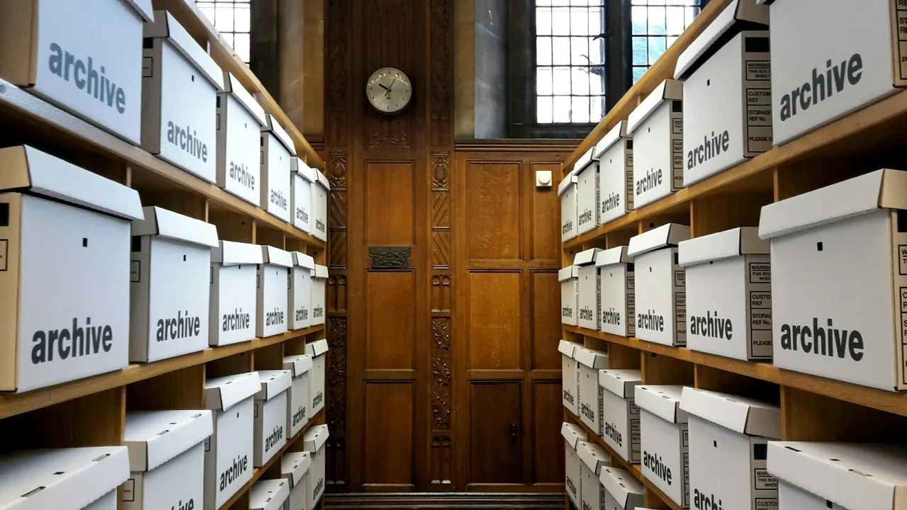 White archive boxes arranged on shelves beside a wooden door