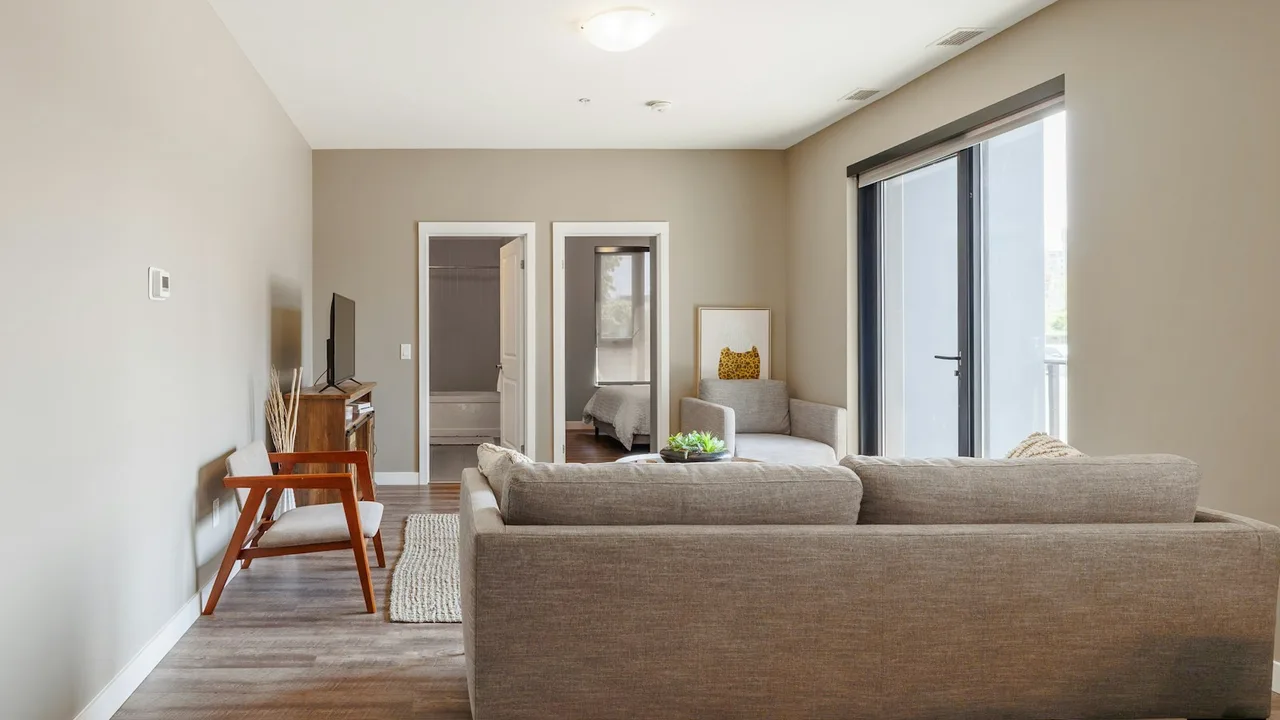 A modern furnished living room with seating and a television