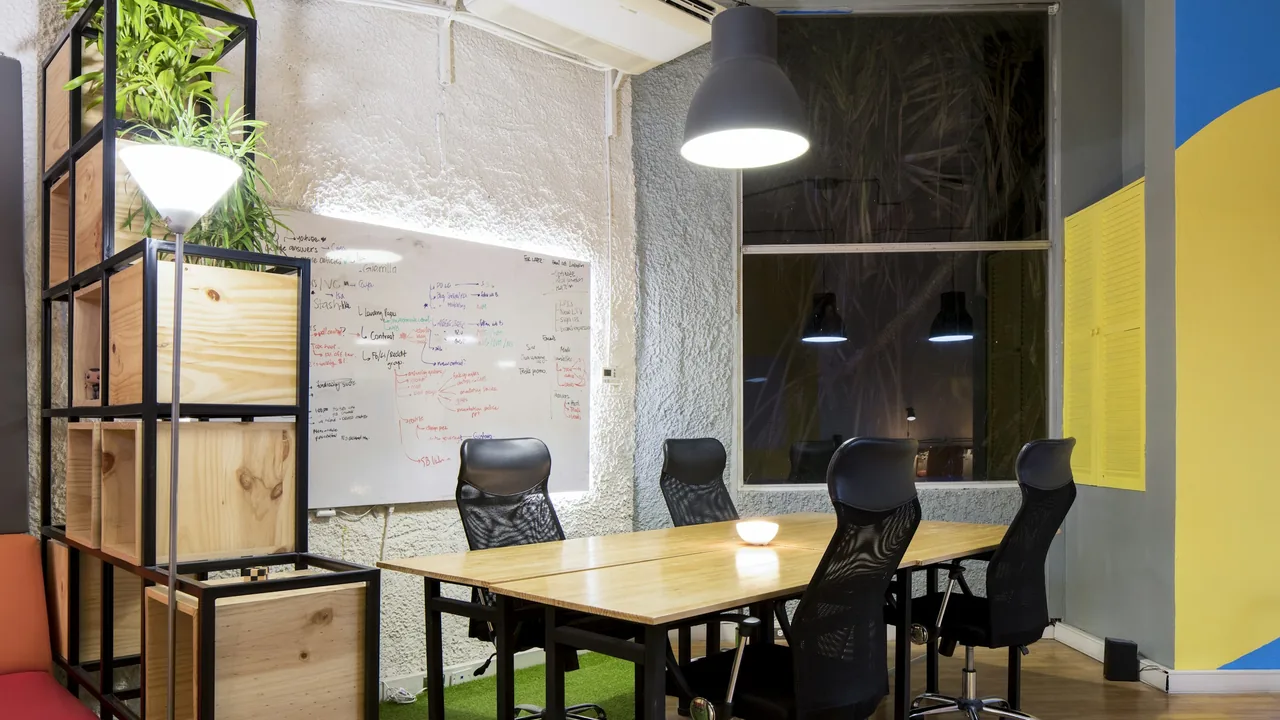 Empty meeting room with a wooden table, black chairs and whiteboard