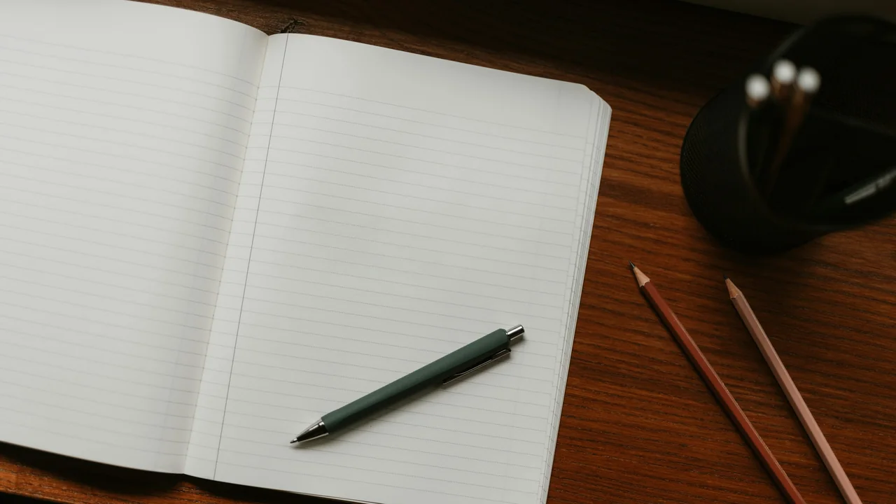 Open notebook with pens and pencils on a desk